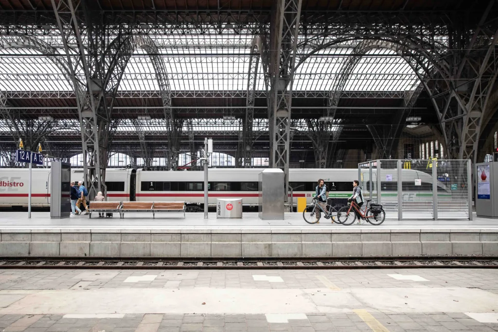 Zwei Fahrradfahrer laufen in einer grossen Bahnhofshalle dem Bahnsteig entlang