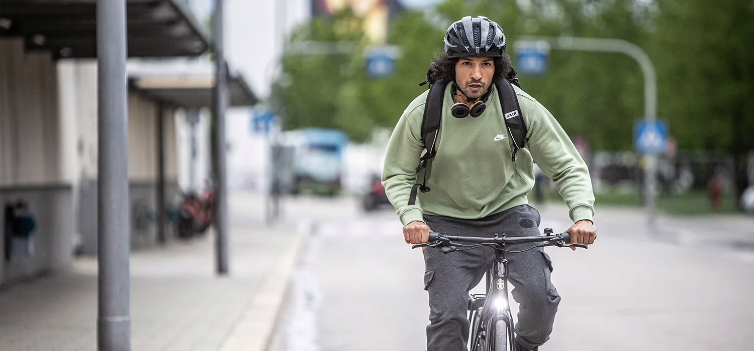 Mann mit Helm und Kopfhörern um den hals fährt dynamisch Fahrrad